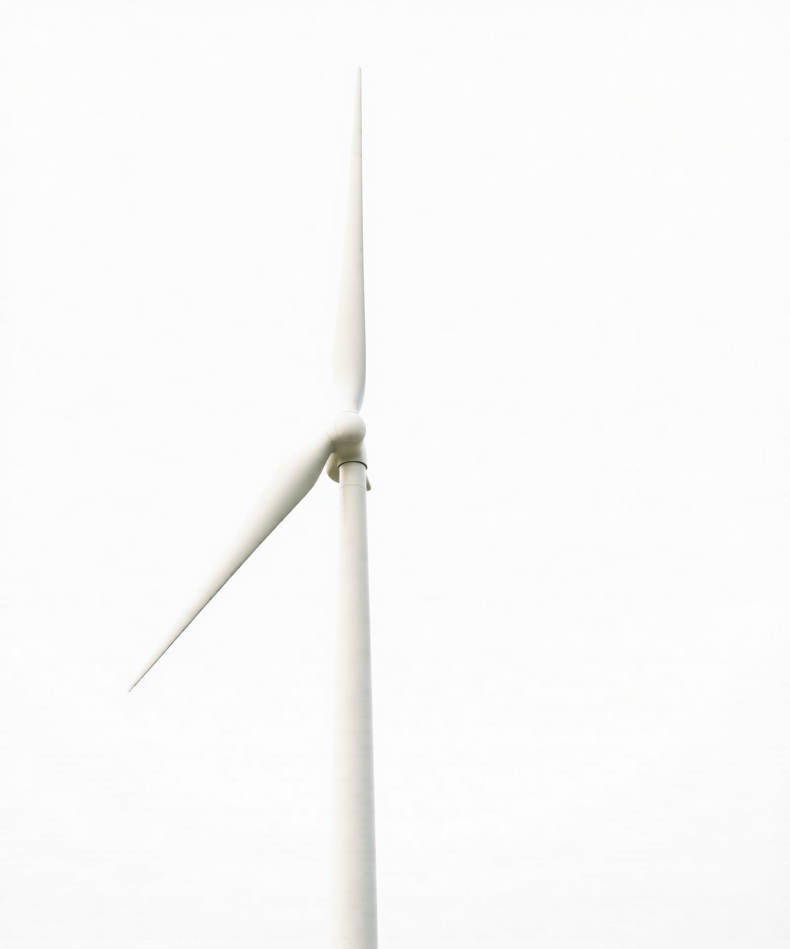 Single white wind turbine against pale sky